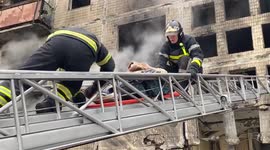 Firefighters carry woman out of residential building hit by Russian shell in Kyiv