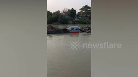 Man brushes his teeth while submerged in river on moving barge