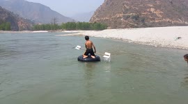 A little boy boating in the huge river through tube of tyre.this is a adventures job.