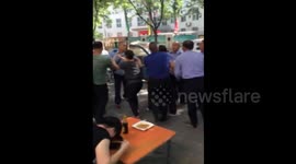 Man calmly finishes noodles as street brawl breaks out around him