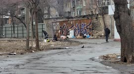 Ukraine: Men Boil Water and Keep Warm Around A Small Fire Next To A Busy Street in Kyiv