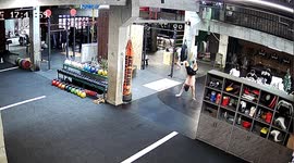 Man practising walking handstand slips as cleaner mops gym floor