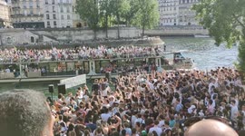 Very huge party along the Seine River shore. Extremely compact crowd. Covid restrictions are really over as spring has started. 21 may 2022. Face to Cathedrale Notre-Dame. Pont Louis Philippe bridge.  Partygoers exchange salutes with boat passengers.