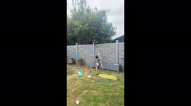 Two year old boy picks a lemon from over the fence from the tree in the neighbors backyard