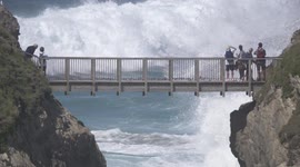UK weather sees huge unseasonal waves pound Cornwall's north coast as spectators on a footbridge linking Porth Island to the mainland are thrilled by the spectacle beneath