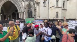 Activists wait judgemebt to sto Rwanda plane outside court listening proceedings on moile pnone