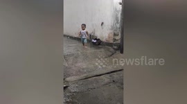 Adorable boy sneaks outside house to play in rain in Indonesia