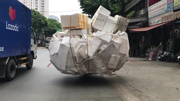 Seriously overloaded motorcycle looks like ball of litter floating across road