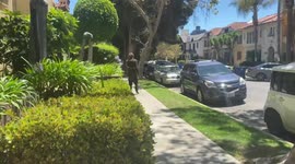 Man walks through central L.A surburbia dragging a heavy metal chain