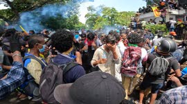 Sri Lankan university students run from tear gas during a protest at prime minister's office