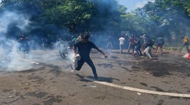A Sri Lankan university student throws back a gas canister back at military