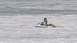 UK Weather, Temporary break in the hot weather, RNLI lifeguards jump big waves at Fistral beach Newquay Cornwall.