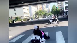 Woman and girl drive go-kart across busy road in China