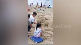 Father forms mermaid out of sand on Chinese beach for daughter