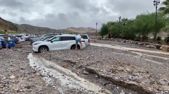 Tourists attempt to free their vehicles from debris flows after flooding in Death Valley National Park