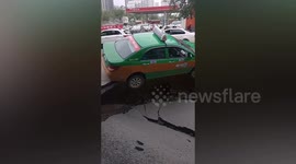 Taxi hangs on edge of sinkhole after road collapses in China