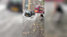 Flash floods have hit London - with one man filmed using a BROOM to try and clear shin-deep water