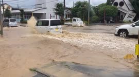 Cars race through muddy water as Japan is hit by torrential rain and flooding