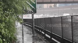 Water splashes onto the pathway as cars drive through floodwater on the A406 in South Woodford