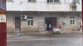 Water tank lands inches away from child after winds blow it off building in China