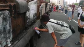 Young boy making graffiti of revenge on destroyed Russian tanks at Millitary parade in Kyiv