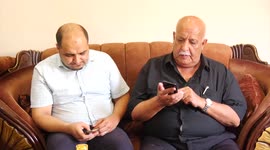 Family of World Vision's head Palestinian Mohammed al-Halabi, watch his picture on a phone after he was sentenced 12 years in prison by Israeli court