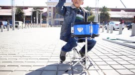 5 year old son sitting in the middle of town playing his special set of drums