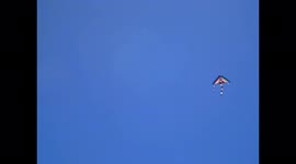 A kite flies in the blue sky in August, supported by the light wind