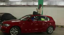 Woman sits on car roof to drive after filling it with shopping bags