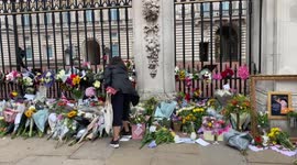 Lady laying flowers outside Buckingham Palace gates after Queen’s death