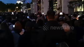 Outside Of Buckingham Palace at night people still come to lay flowers as a tribute to the Queen