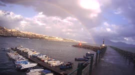 A gigantic rainbow, immediately after the rain, leaves the sea and goes towards Vesuvius