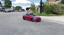 Kid drifting in slow motion in a Radio Flyer Tesla red car