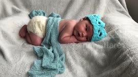 Adorable footage shows one of the first babies born under the reign of King Charles III wearing a woolly CROWN