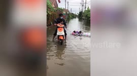 2-year-old relaxes on inflatable raft being pulled across flood