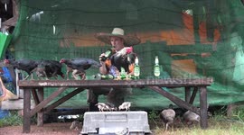 A man drinking beer and talking with some chickens on a table.