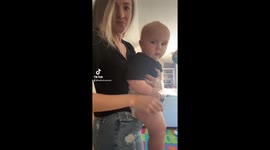 Mom holds baby boy as he kicks his legs fast doing the trending running video.