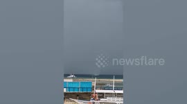 Waterspout forms next to beach and passes by boats in the Philippines