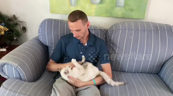 My son is holding his cat, who freaks out whenever the door is opened.