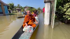 Buddhist monks use rowing boats to deliver supplies to families stranded in floods in Thailand