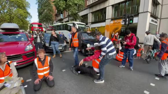 London cabbie drags Just Stop Oil protesters from Park Lane, beside Aston Martin shop they covered with paint