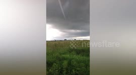 Terrifying funnel cloud appears over field as landspout tornado swirls nearby