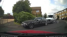 A car drivers carefully around a blind bend when it's faced with a Mercedes driver going very fast, then the driver goes up the pavement scraping his car