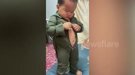 Adorable moment chubby toddler tries his best to zip up pilot suit