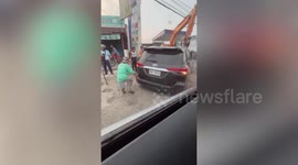 Bungling motorist gets stuck in wet concrete when he drives through newly-paved road