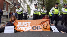 Just Stop Oil protesters holding a banner are surrounded by police in Central London.