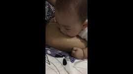 Cute baby tries to blow bubbles on mum's leg.