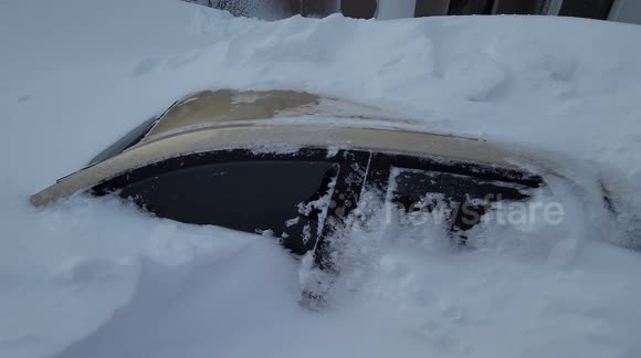 Walking over car submerged by snow as Buffalo, New York, is hit by historic storm