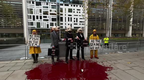 Activists wear fish head costumes and pinstripe suits against overfishing in front of London's DEFRA