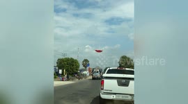 Dust devil tornado blows away flying sun umbrella on road in Cambodia